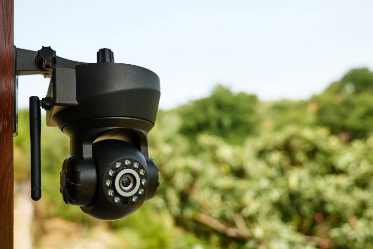 Security camera on the wall of a building with nature in background. CCTV surveillance security camera video equipment. Home security system concept. Safety system area control outdoor with copy space.